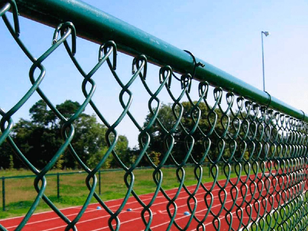 Alambrado revestido em verde cercando uma pista de atletismo