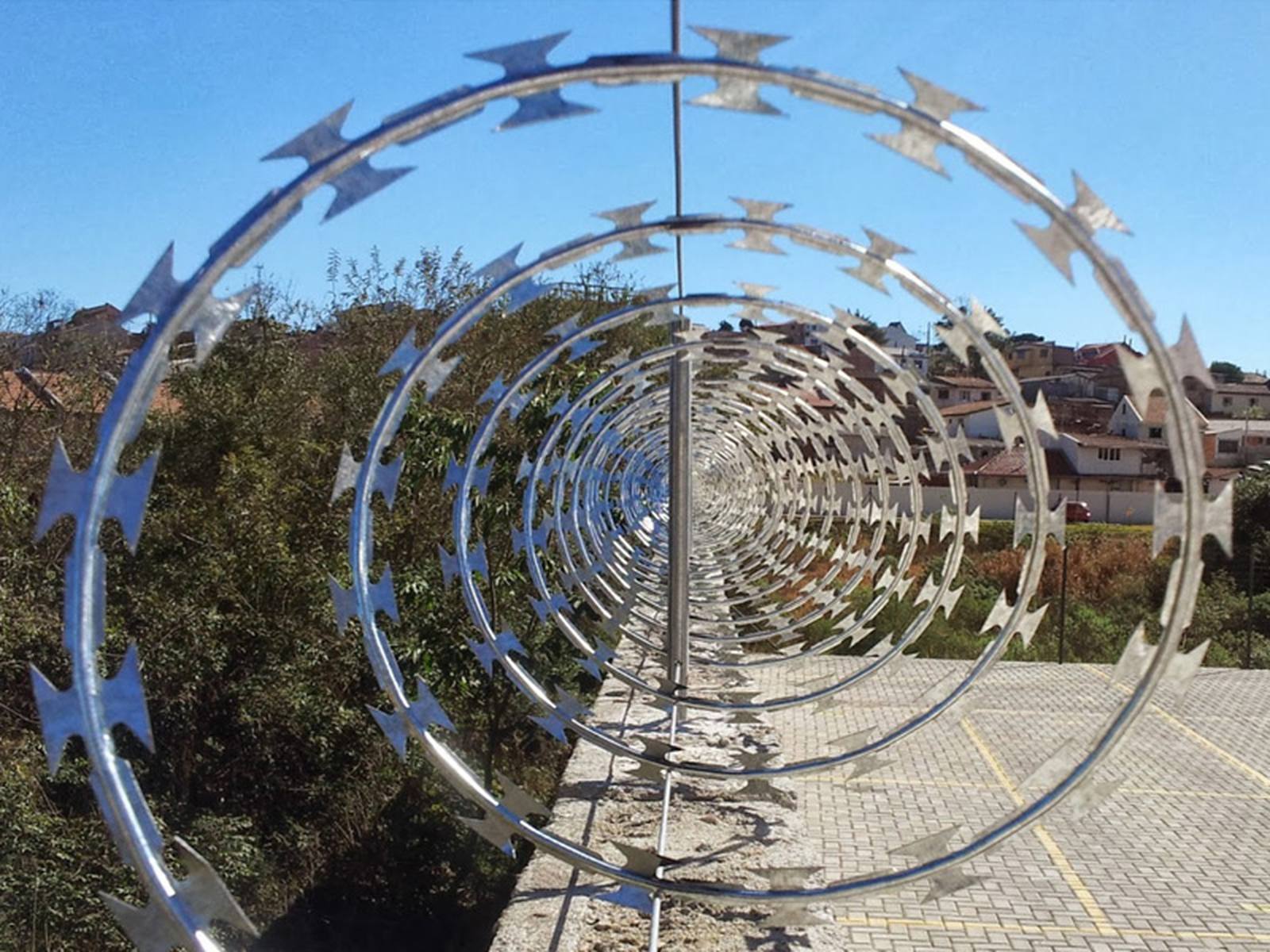 Concertina de aço instalada sobre muro, vista em perspectiva ao longo do perímetro