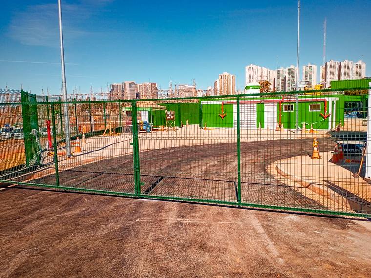 Portão metálico verde de duas folhas em telado soldado, na entrada de uma subestação